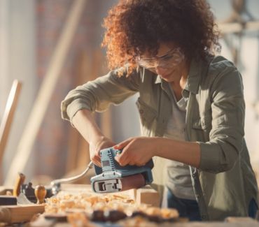 A woman using power tools to create something out of wood - The Skills Required To Work In The Woodworking Industry